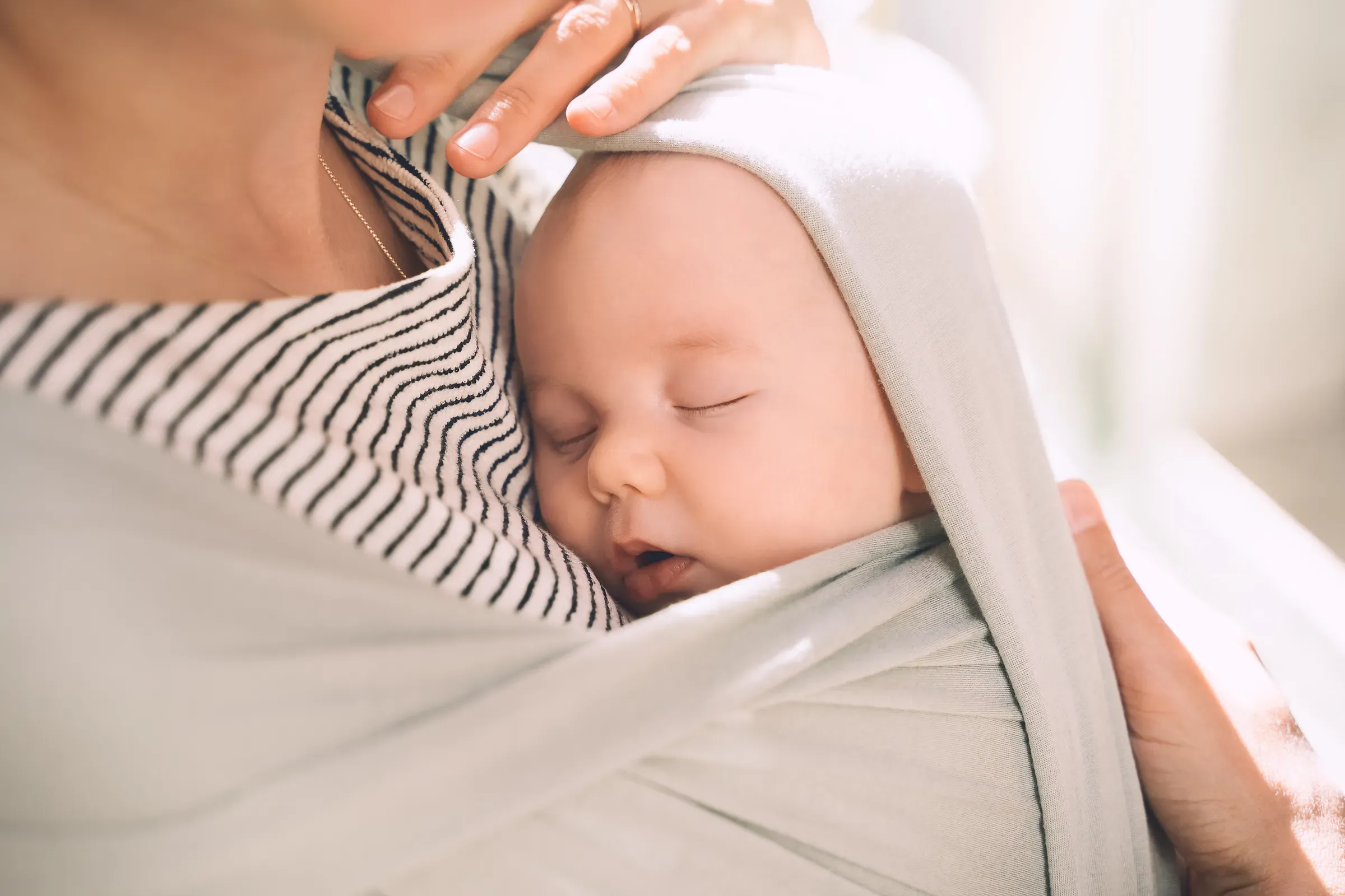 Babywearing. Mother and baby on nature outdoors. Baby in wrap carrier. Woman carrying little child in baby, baby carriers ecommerce