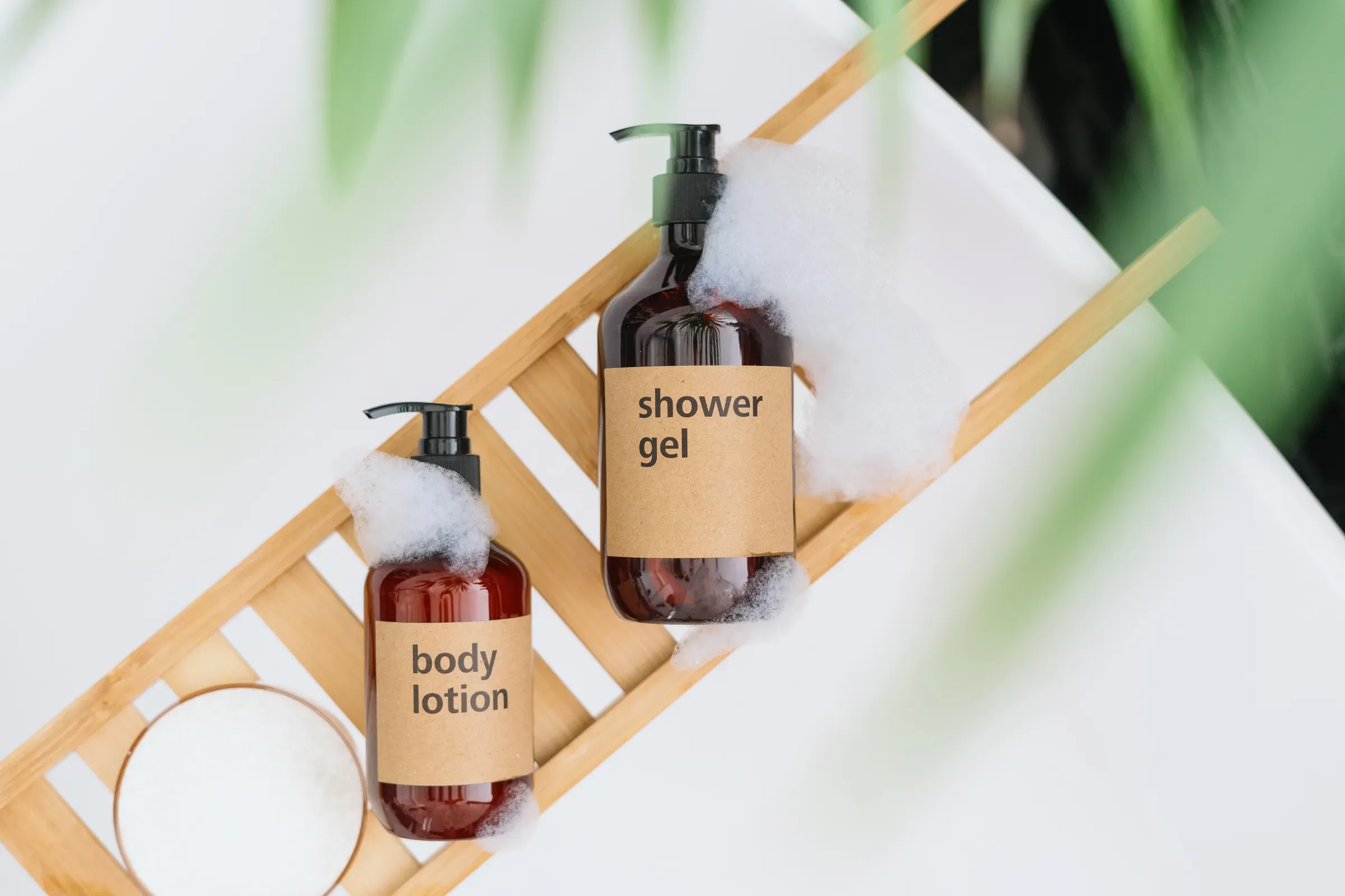 Shower gel and body lotion on wooden tray on bathtub, top view, bath & body ecommerce