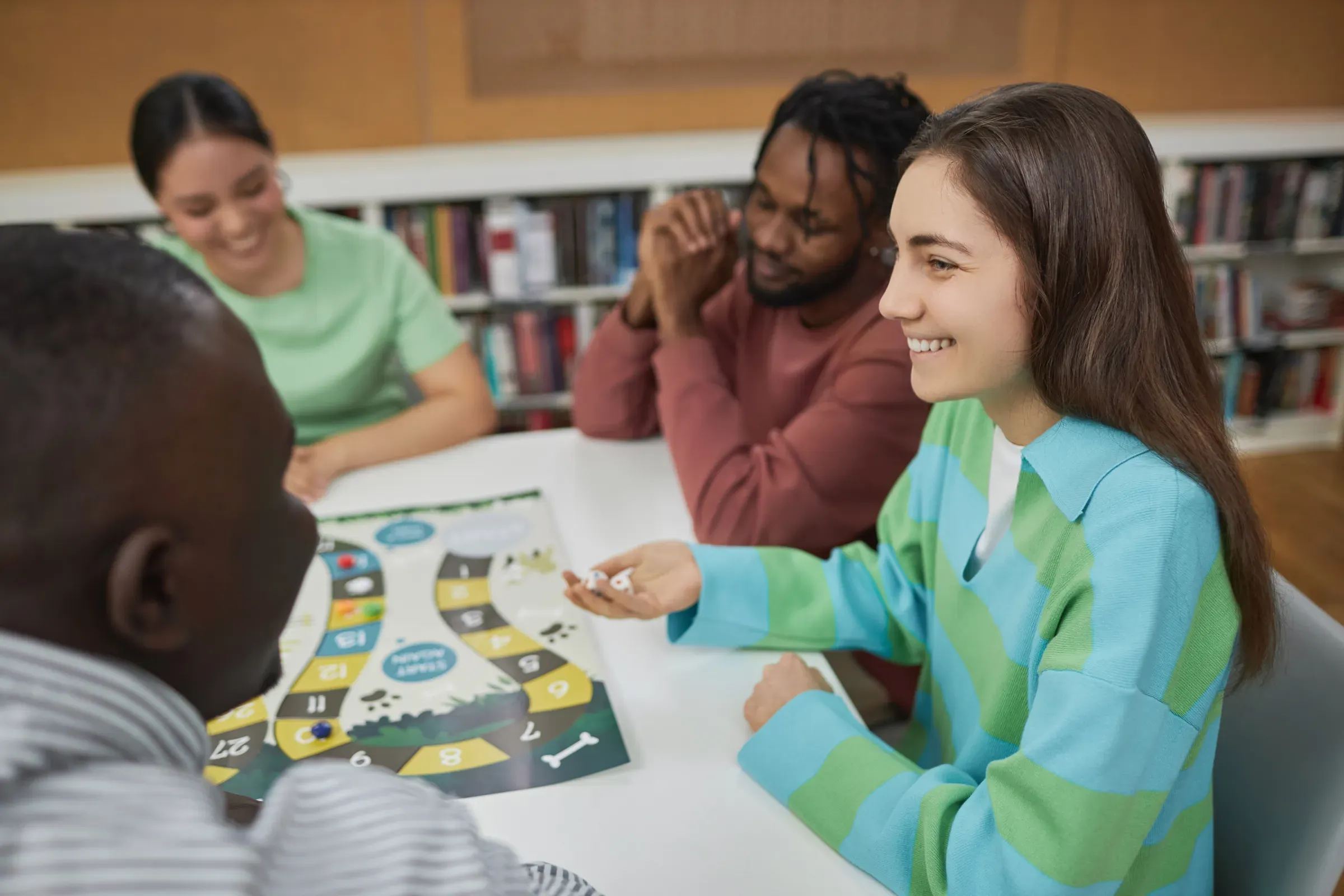 Smiling young woman playing board game with group of friends, board games & puzzles ecommerce