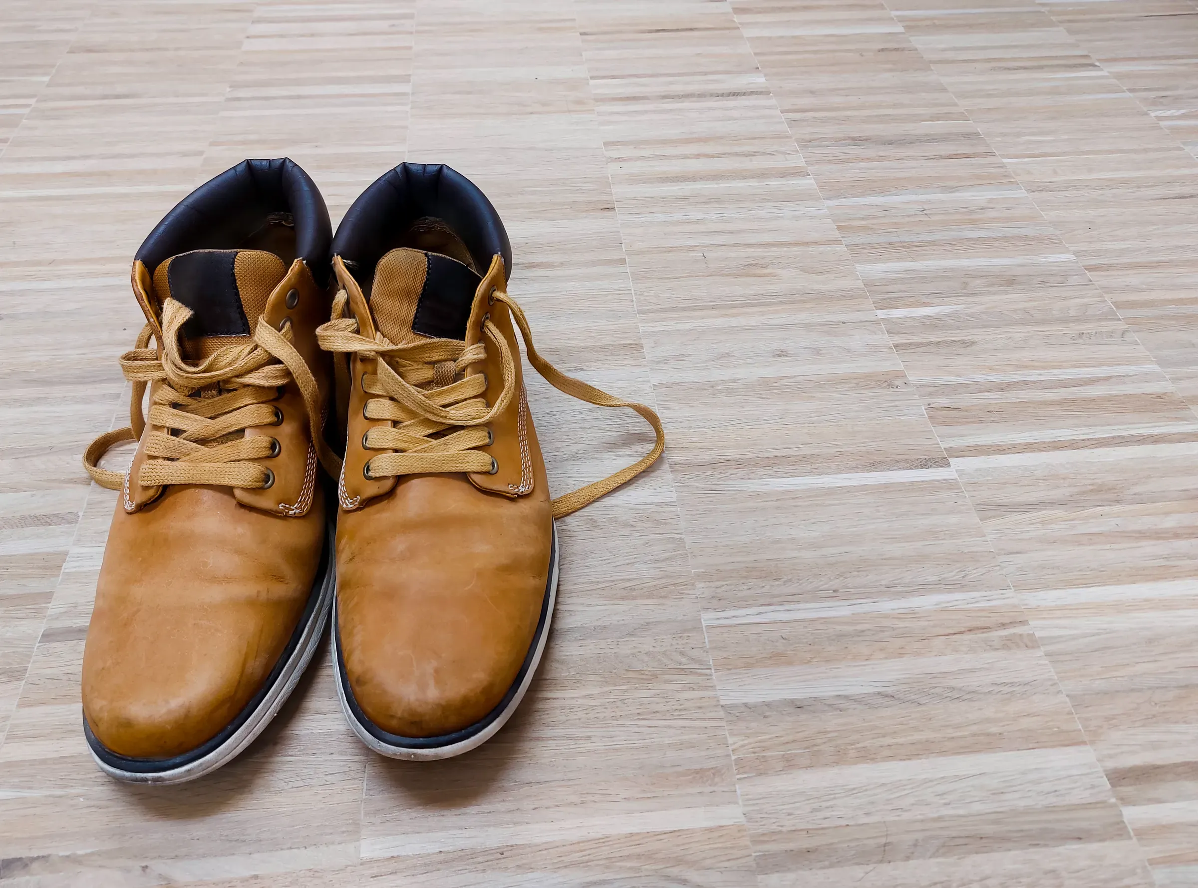 Pair of old light brown leather boots on wooden floor, boots ecommerce