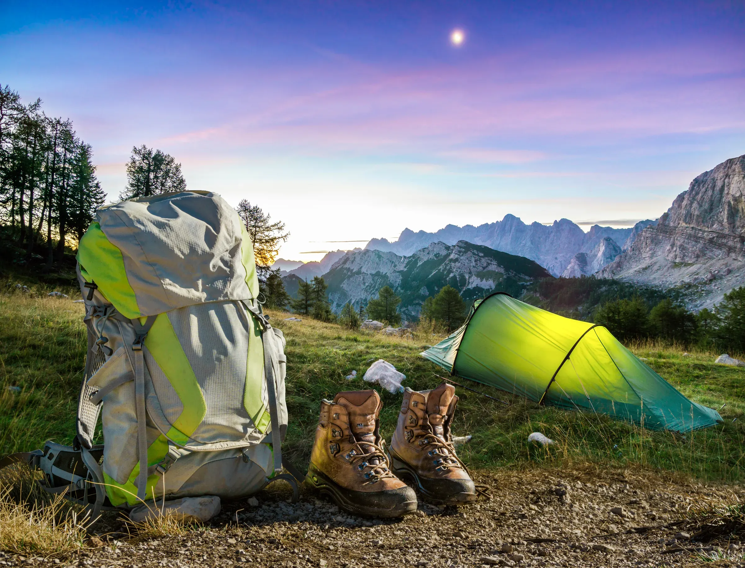 Hiking Equipment, Tent, Backpack and Boots under a moon night sky at amazing twilight hour. Alps, Triglav, camping & hiking gear ecommerce