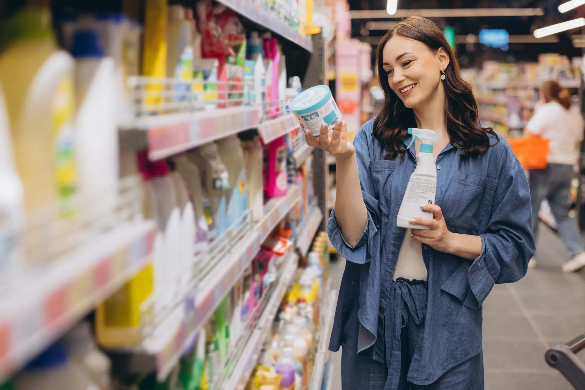 Woman choosing household cleaning products from a shelf in supermarket aisle, comparing different brands for, cpg & household ecommerce