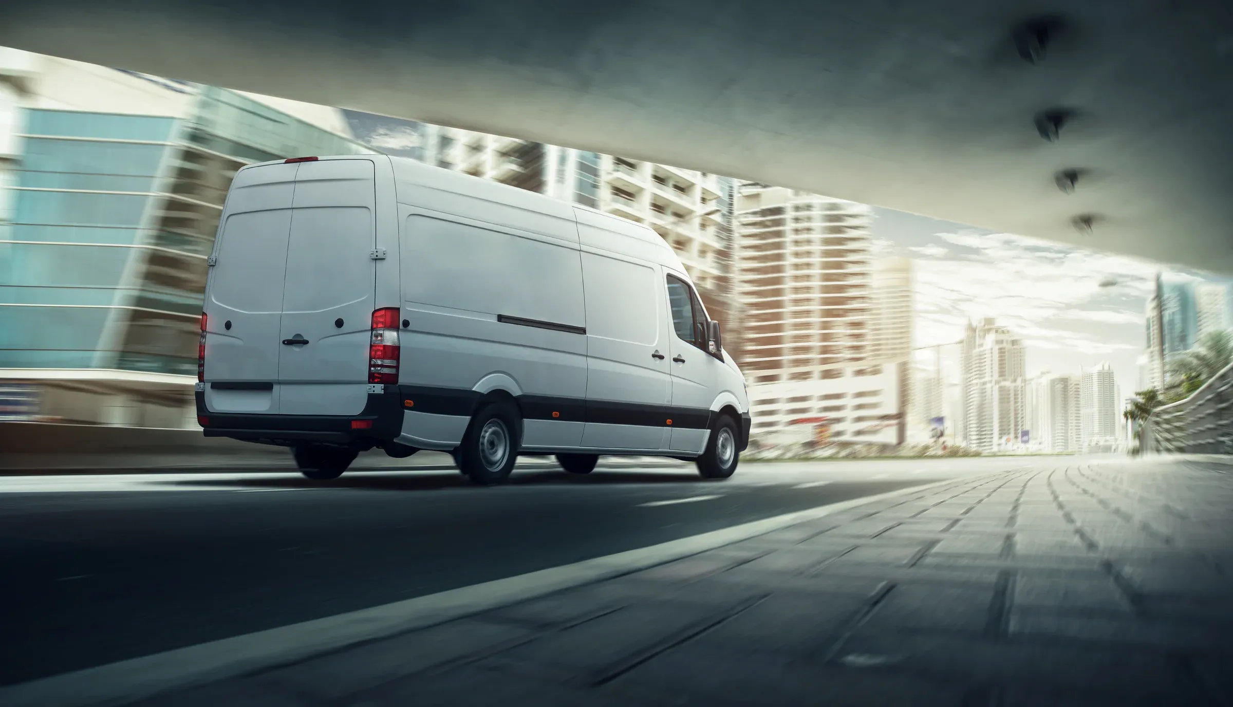 A white delivery van moving through a city street