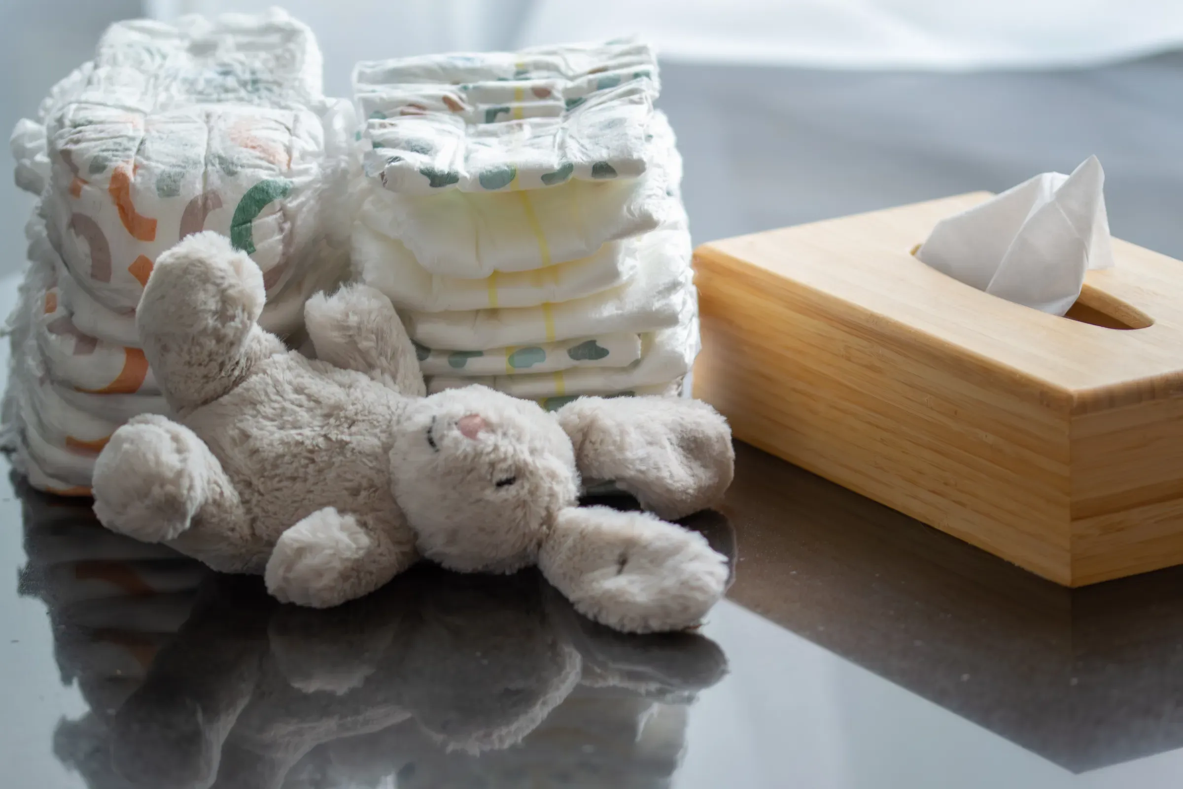 Stack of diapers with a toy bunny and a box of napkins on the table. Newborn nappies, diapers & wipes ecommerce