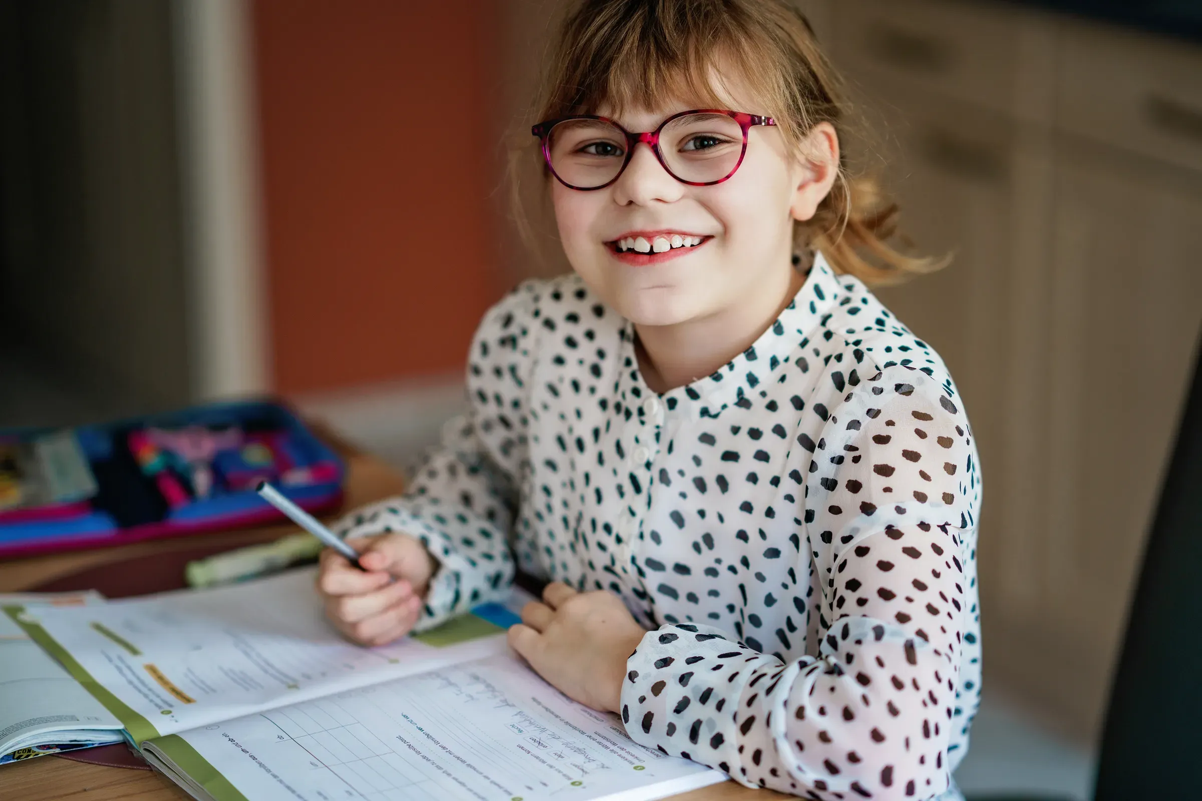 Little girl with glasses studying at home, focused child reading workbook at desk, education and learning, educational workbooks ecommerce