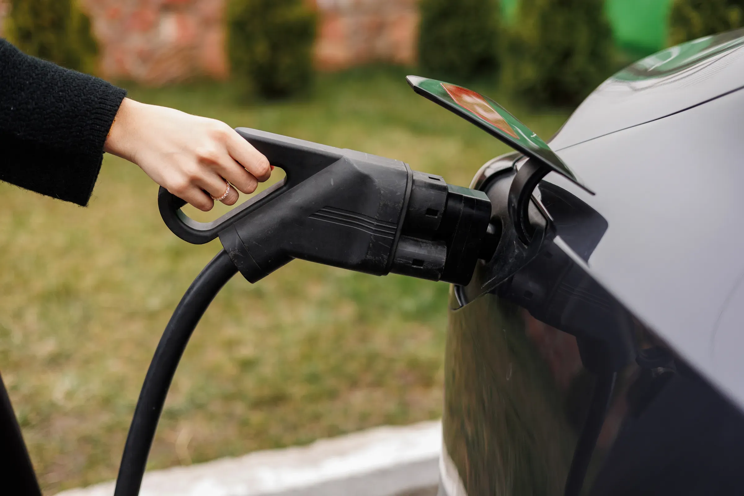 Unrecognisable woman inserting EV charger plug from public or home charging station for modern electric or, ev chargers & accessories ecommerce