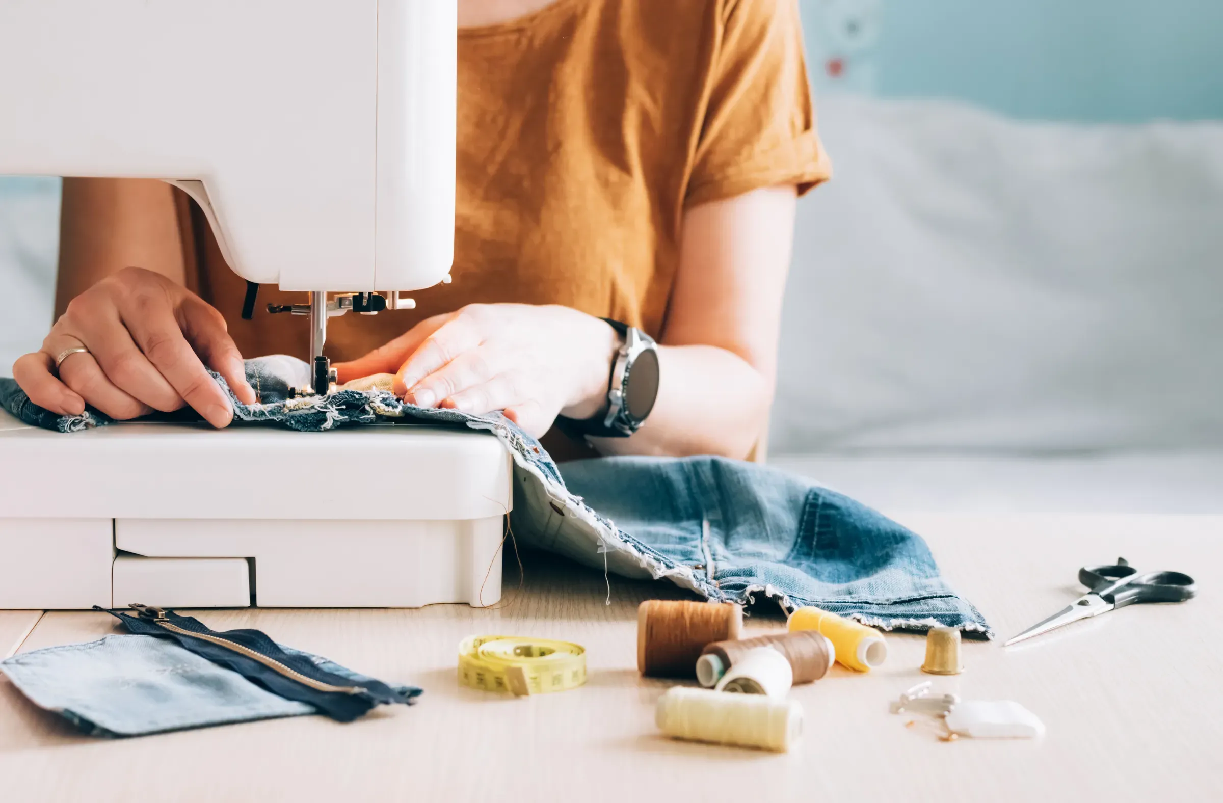 A woman tailor works at sewing machine sews reuses fabric from old denim clothes, fabric & sewing ecommerce