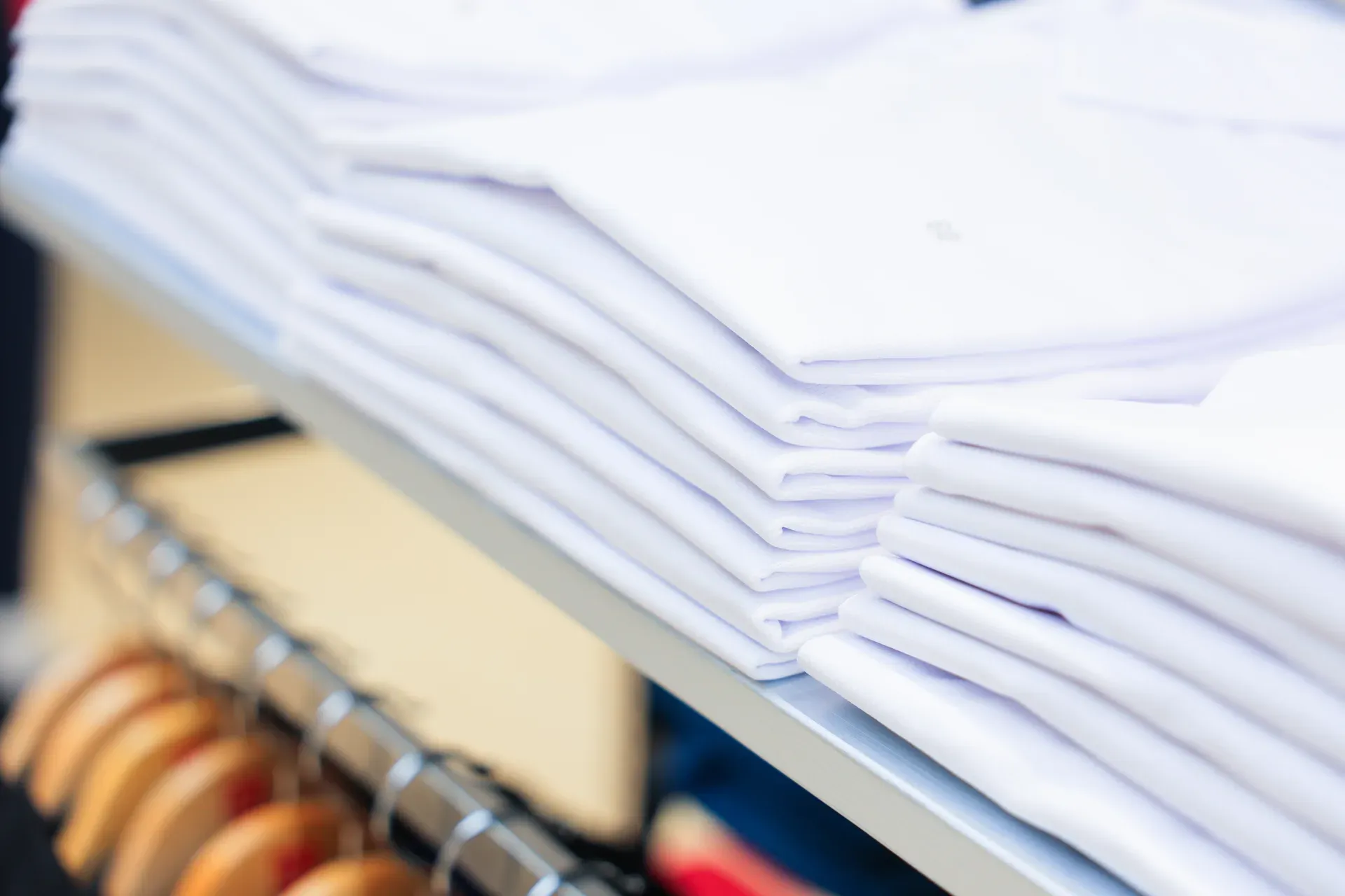 Neatly folded white polo shirts stacked on a retail display table