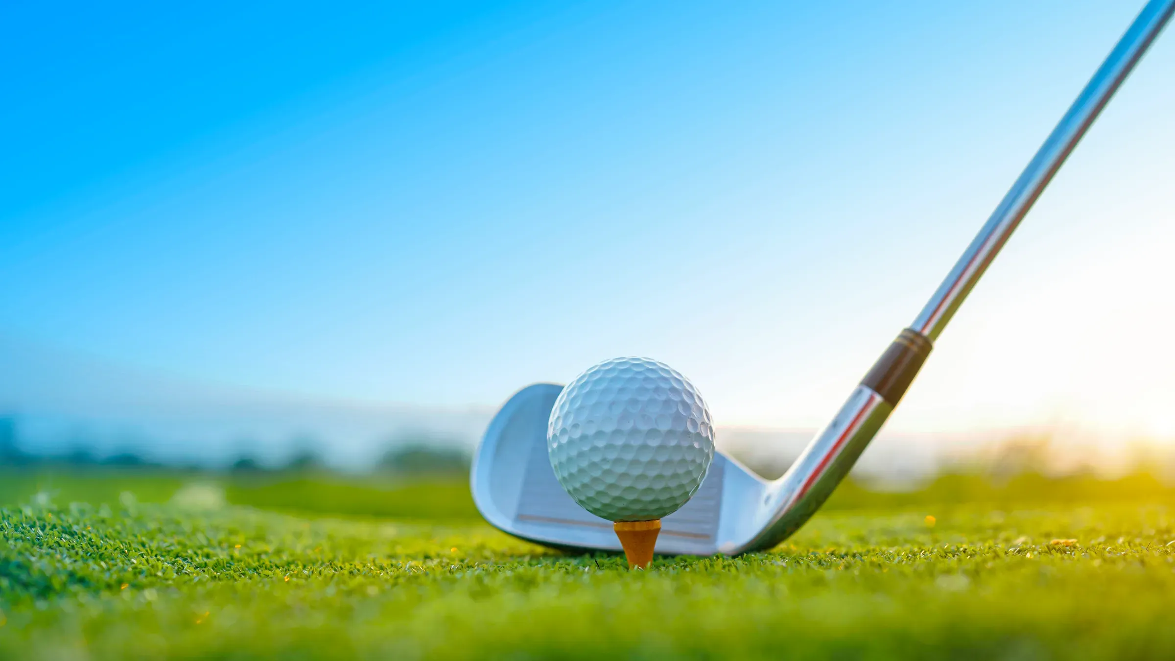 Golf clubs and golf balls on a green lawn in a beautiful golf course with morning sunshine, golf equipment ecommerce