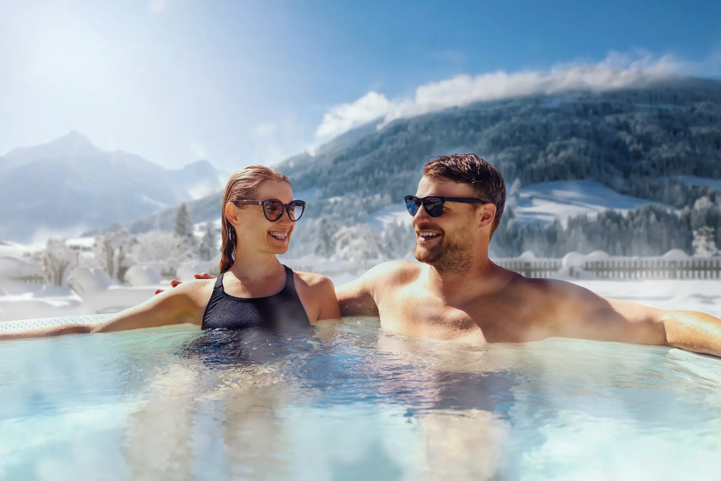 Happy couple relaxing in outdoor hot tub at ski spa resort. winter vacation, hot tubs & saunas ecommerce