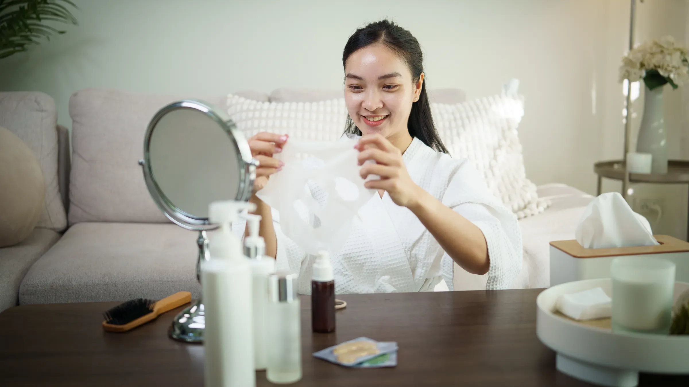 Smiling woman in bathrobe preparing to apply a sheet mask during skincare routine at home, k-beauty ecommerce