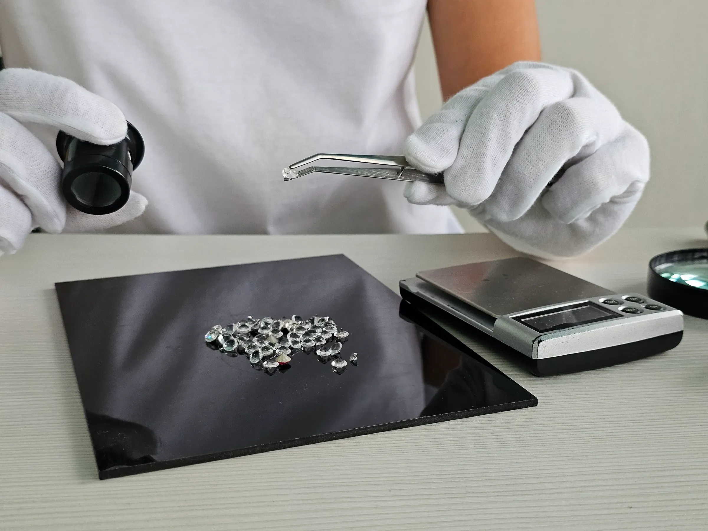 Woman jeweler sorts diamonds with tweezers on wooden table with scales, lab-grown diamonds ecommerce
