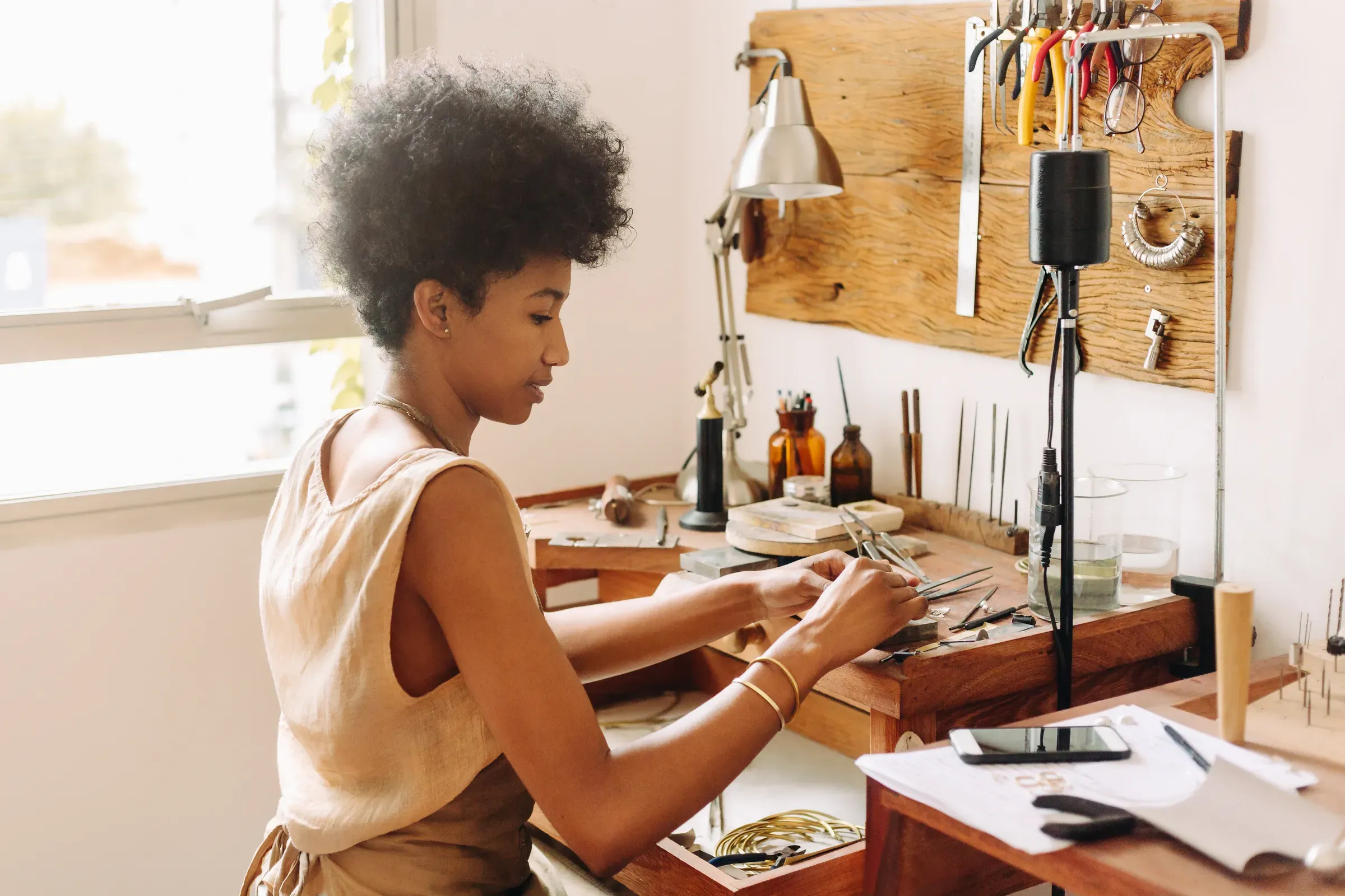 Woman making handmade jewelry in her workshop, made-to-order & custom products ecommerce