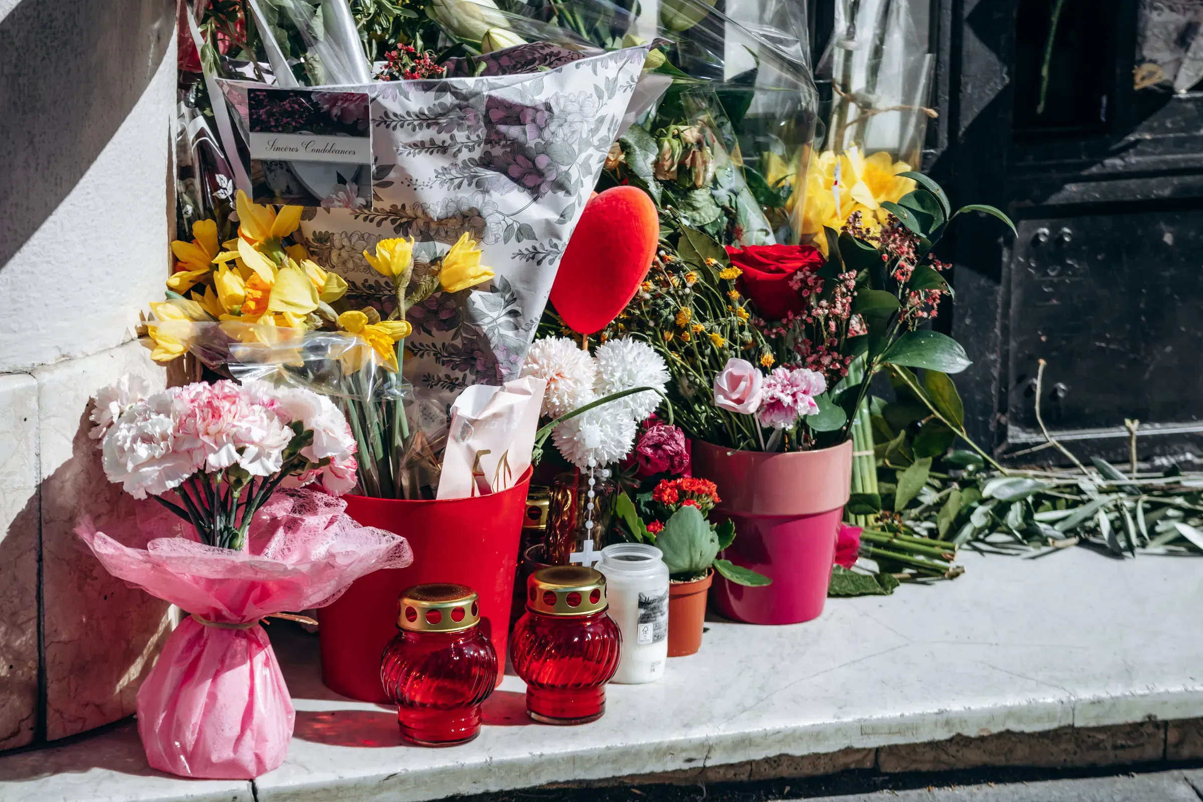 Close-up of memorial with flowers, candles and photographs placed at the entrance of a residential building, memorial & sympathy gifts ecommerce