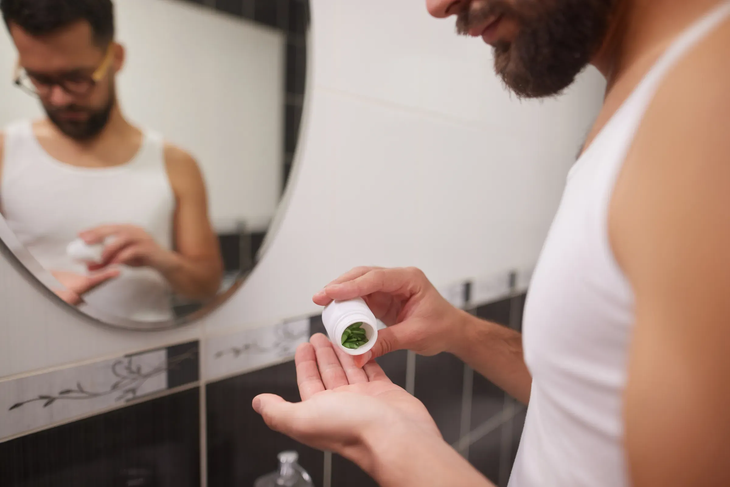 Man taking vitamin supplements as part of morning health routine, men's health ecommerce