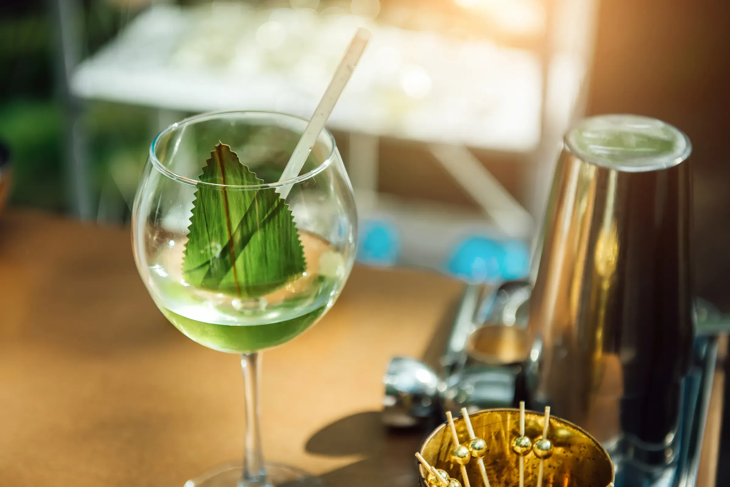 Summer alcoholic or non-alcoholic cocktail in a wine glass with a green leaf and a straw in the sunlight., non-alcoholic drinks ecommerce