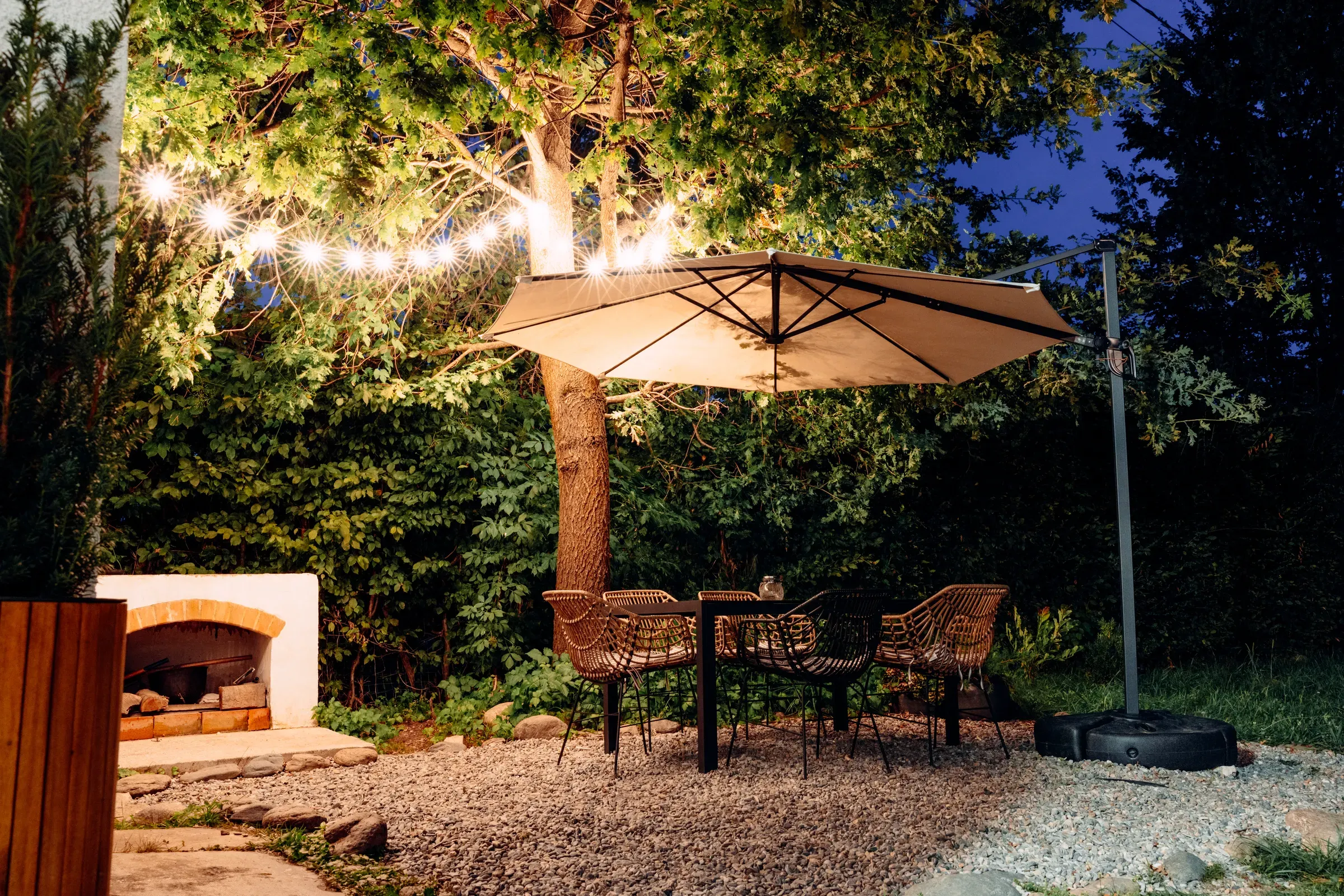 Outdoor patio with table, chairs, and umbrella illuminated by string lights, outdoor lighting ecommerce