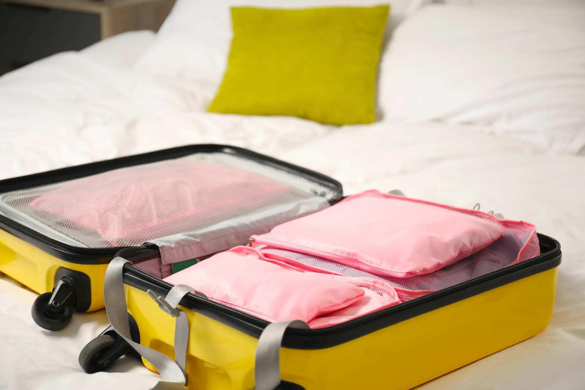 Open suitcase with packing cubes on bed indoors, closeup, packing cubes & organizers ecommerce