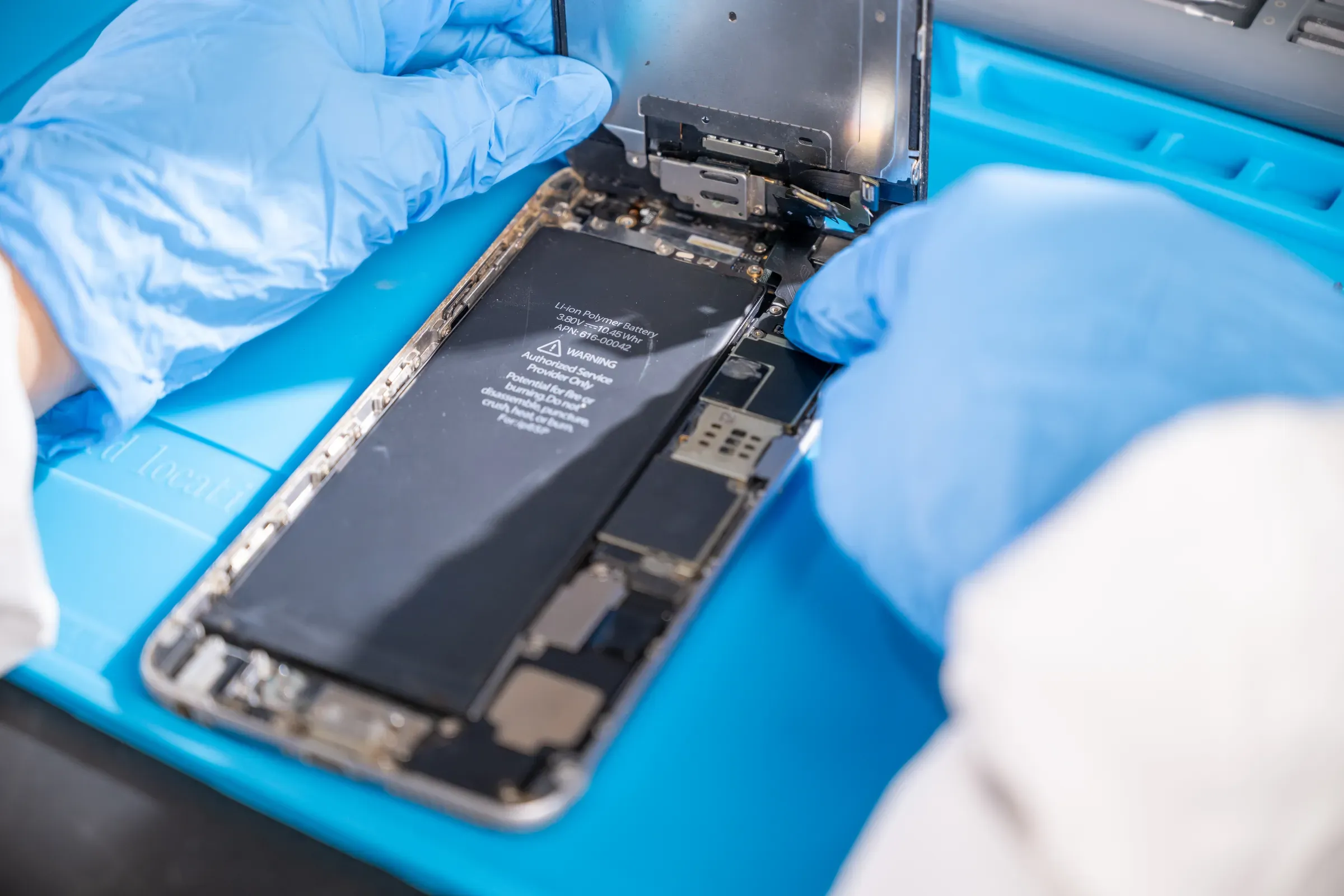 Smartphone technician repairing disassembled mobile phone hardware, refurbished electronics ecommerce