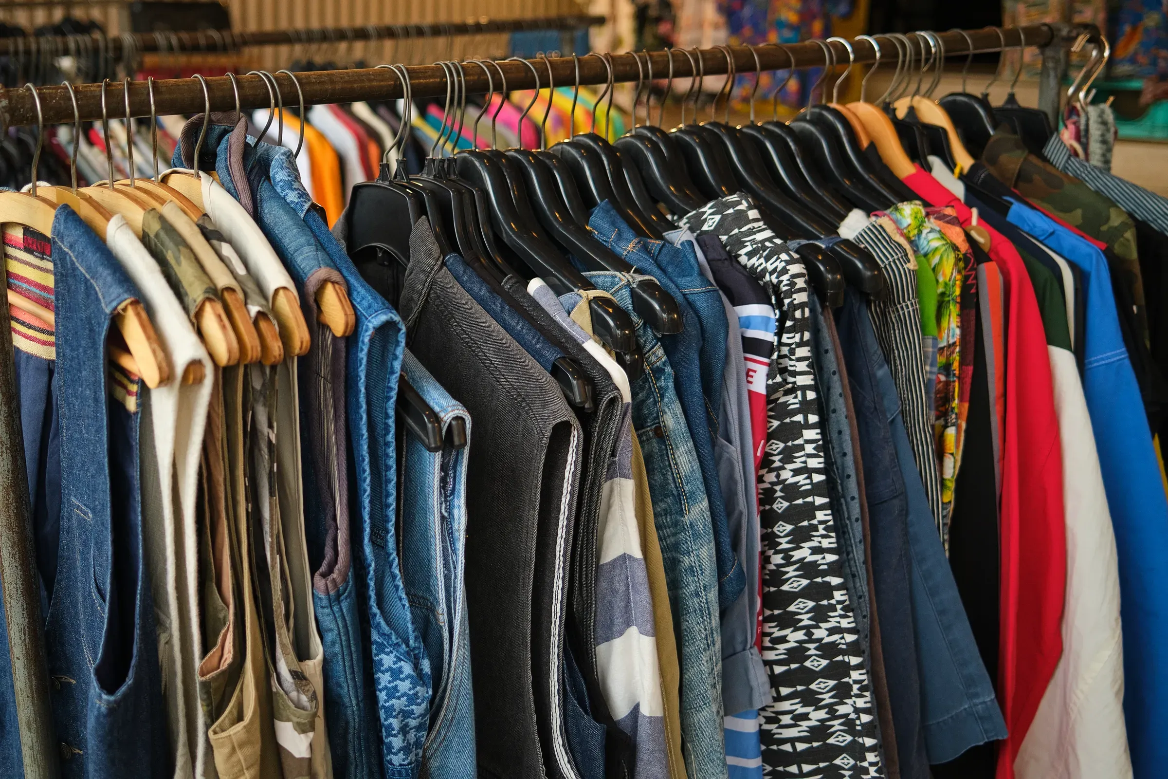 Vintage Clothing Rack in Second Hand Store. Assorted denim and plaid garments displayed on hangers inside a, resale & refurbished ecommerce