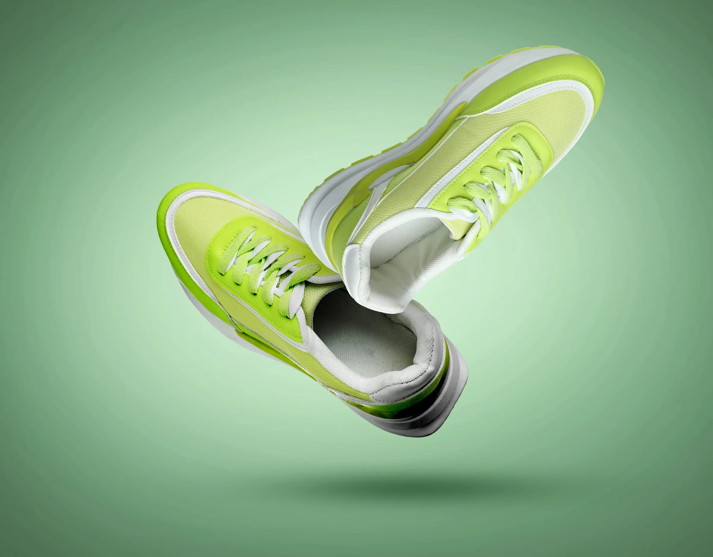A pair of green sneakers floating against a green background