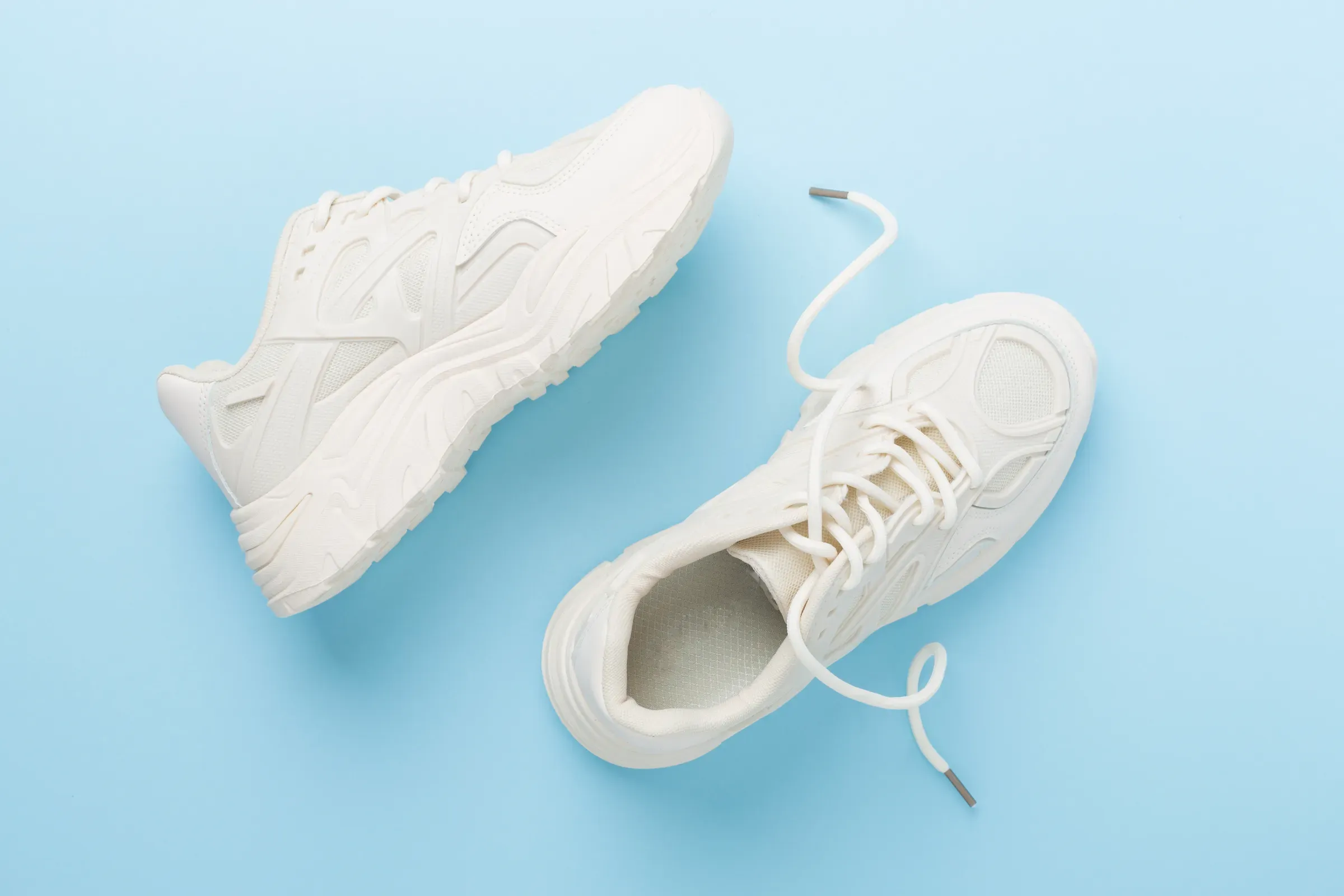 White woman trendy sneakers on color background, top view, sneakers ecommerce