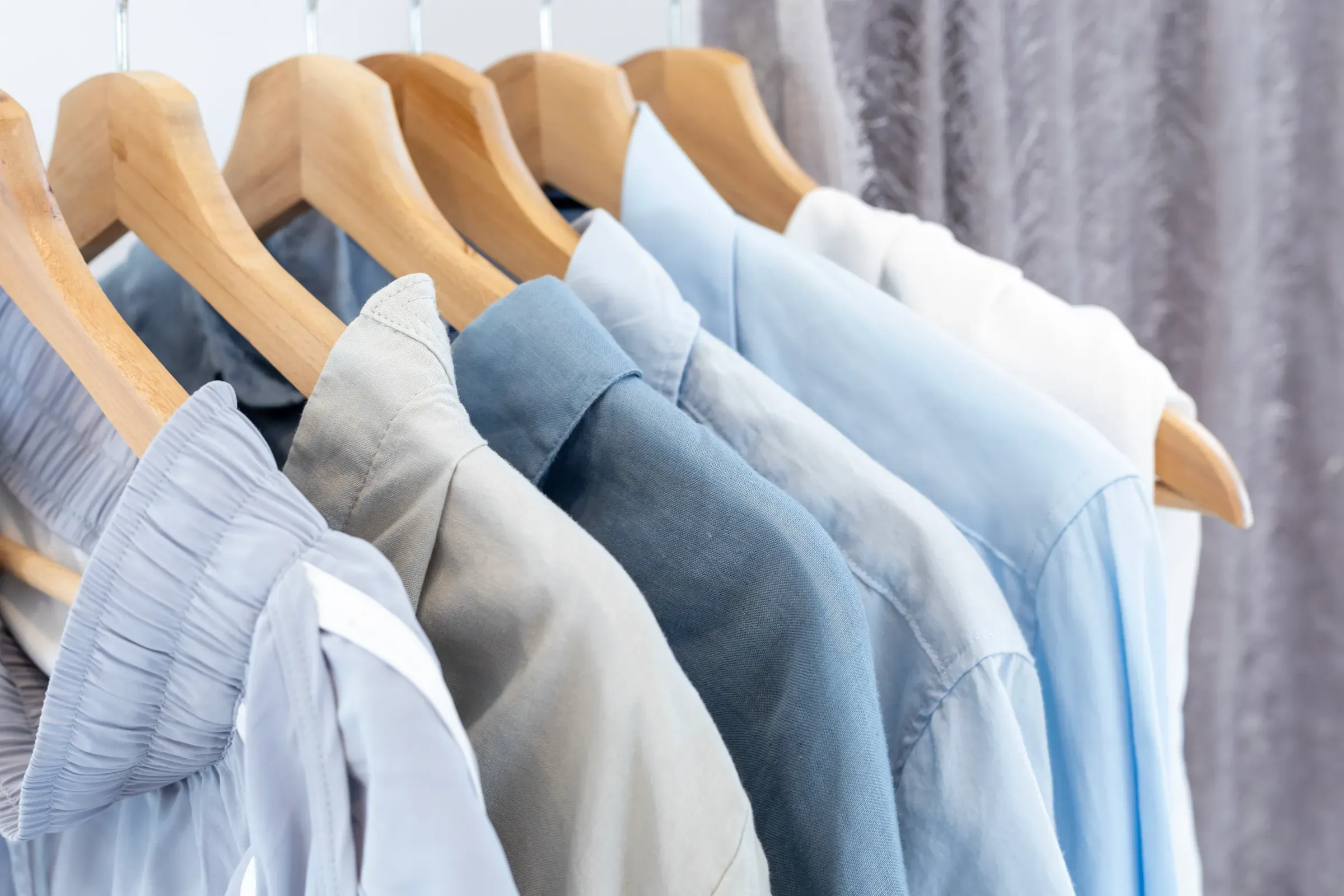 Rack of blue and grey tone cotton shirts on the open closet at second hand retail shop for eco friendly, sustainable fashion ecommerce