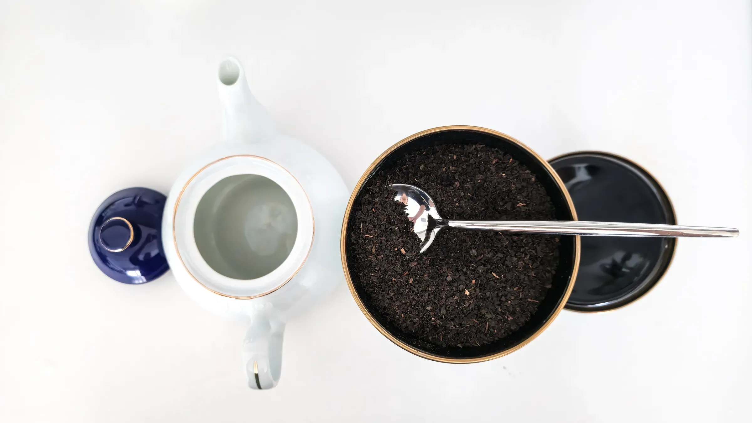 Preparing traditional loose leaf black tea in a white porcelain teapot, top view, tea ecommerce