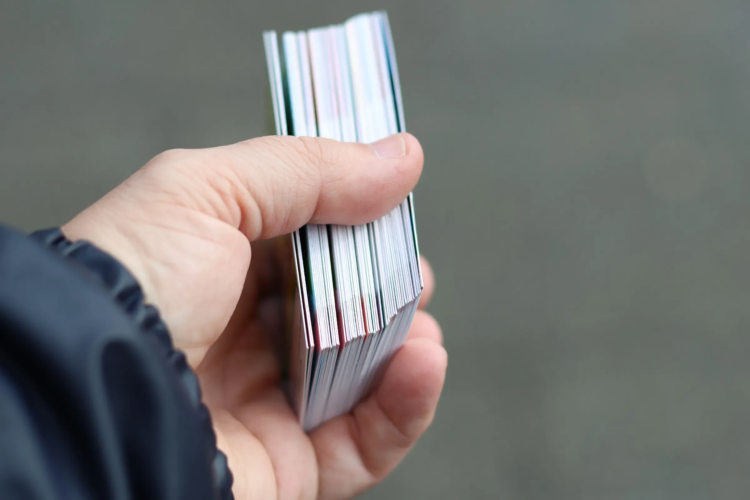 A hand holding a pack of trading cards, trading cards & collectibles ecommerce