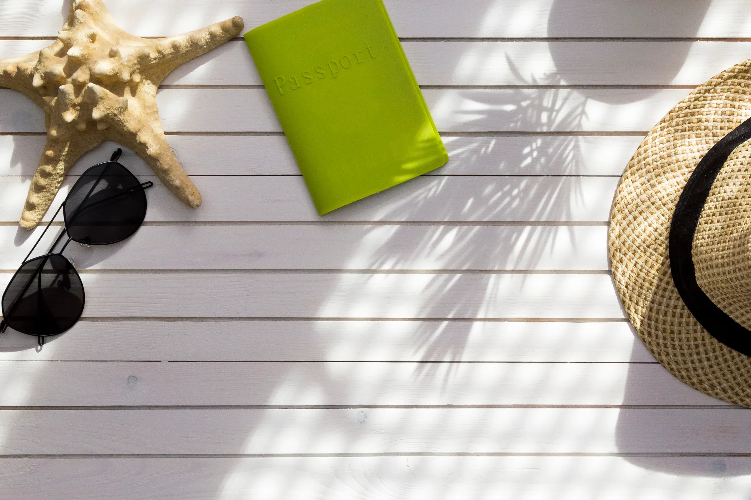 Summer travel accessories flat lay on white wood background. Passport, hat, sunglasses and starfish for, travel accessories ecommerce