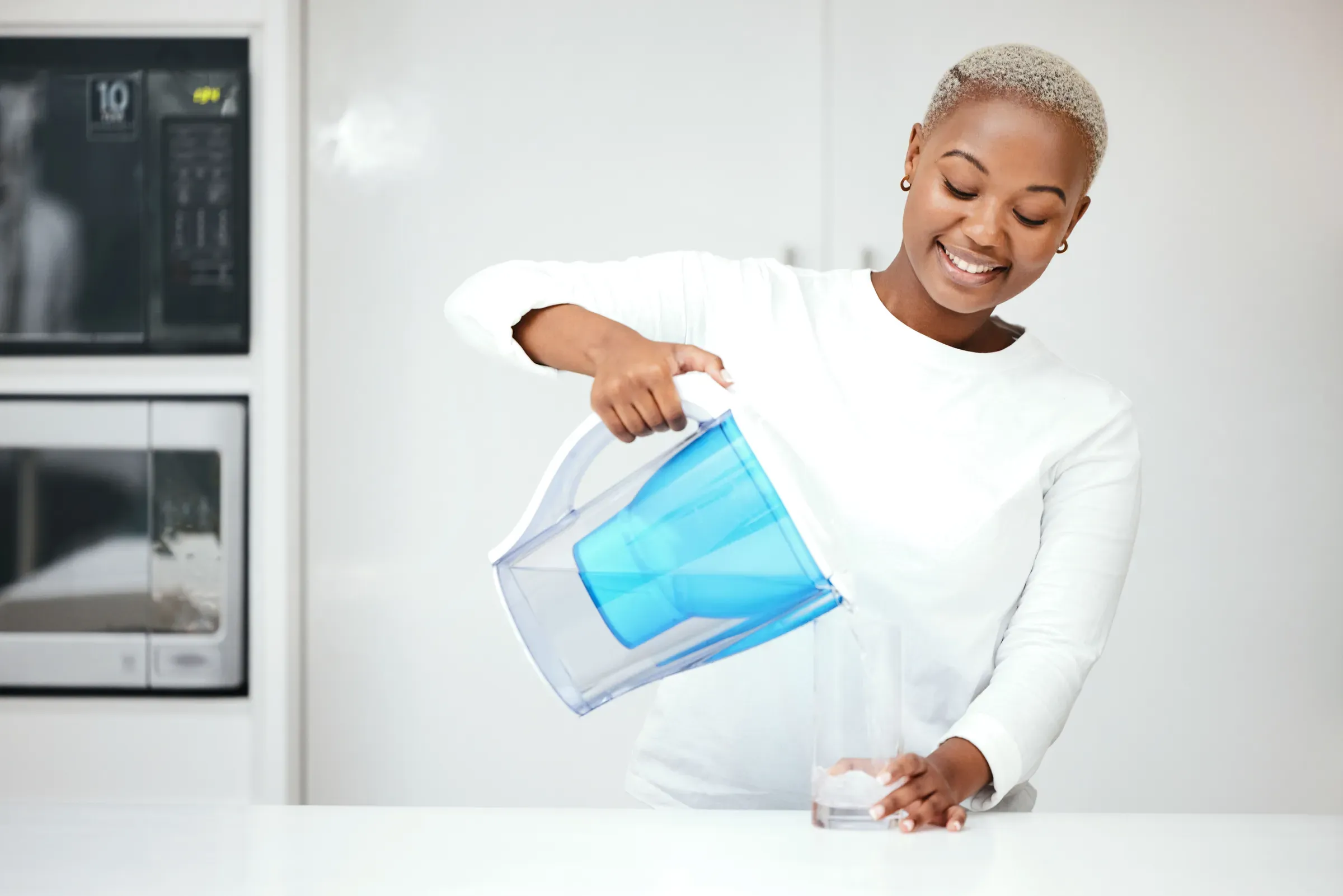 Water, filter and black woman with jug in kitchen to refresh with glass, liquid and cold hydration. Happy,, water filters & bottles ecommerce