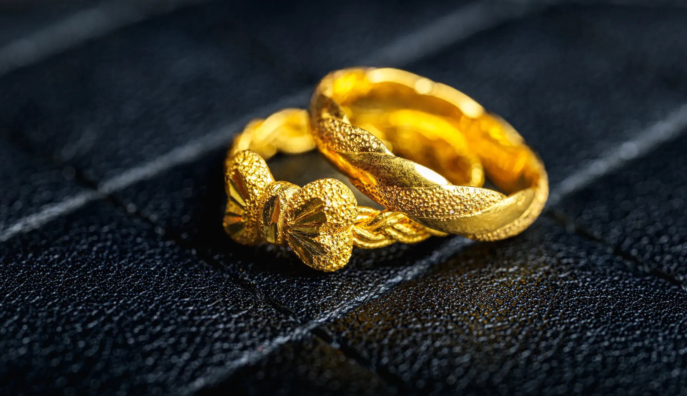 Pair of Gold Twisted Rings on dark textured Background, Top view, wedding bands, couple rings, wedding bands ecommerce