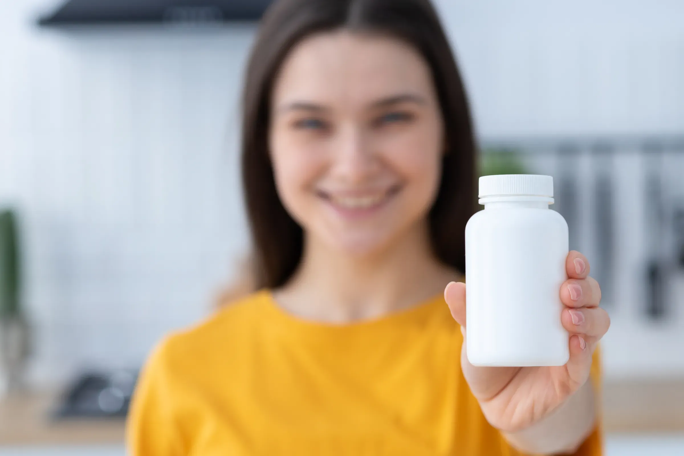 Happy young Caucasian woman holding bottle of dietary supplements or vitamins in her hands. Close up. Healthy, women's health ecommerce