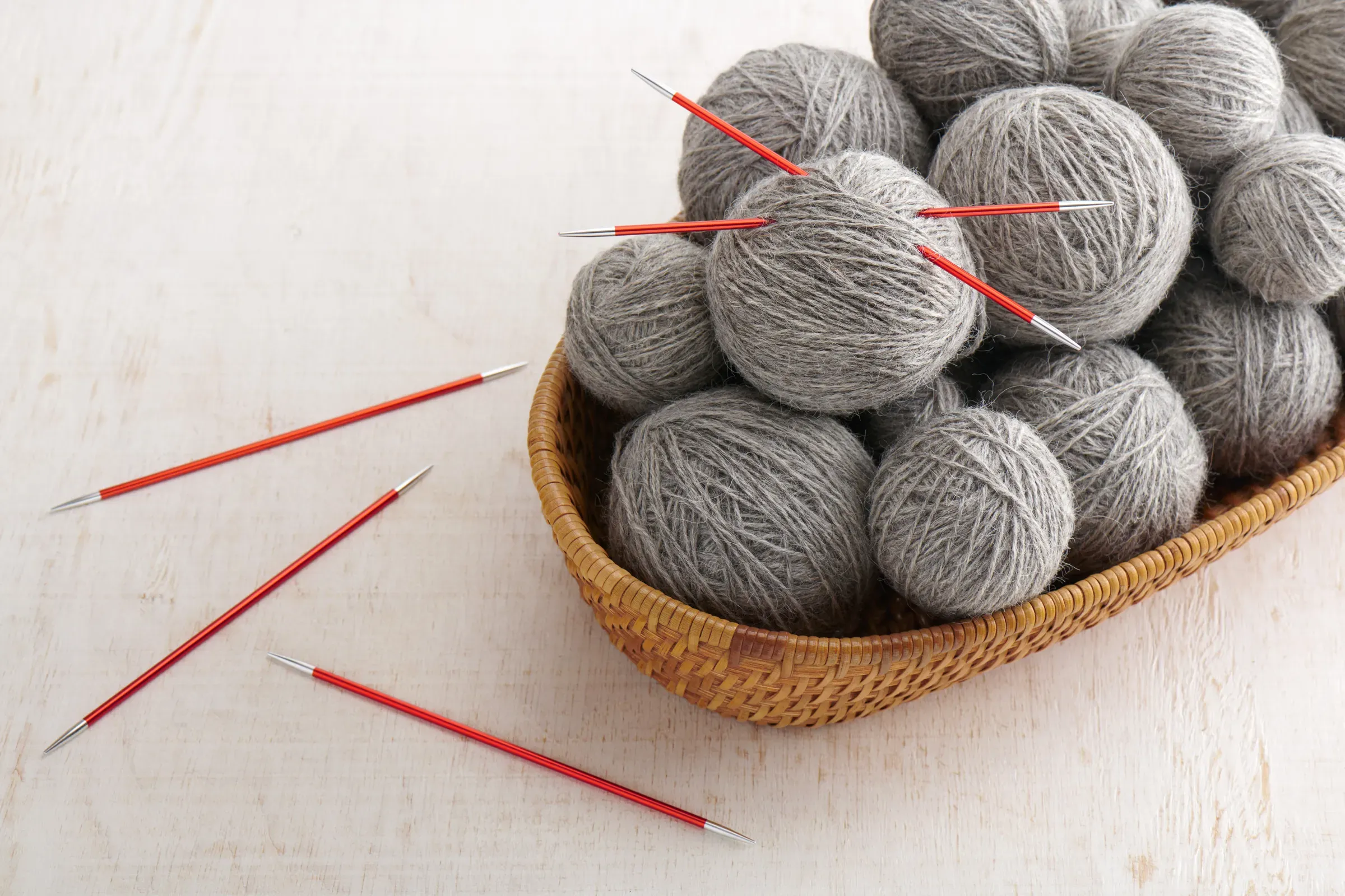 Double pointed knitting needles and balls of yarn in basket, yarn & knitting ecommerce